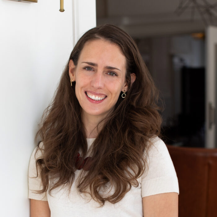 portrait of katie lefler, smiling and standing outside in sunlight