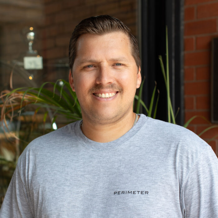 portrait of tim kuehn, smiling and standing outside in sunlight